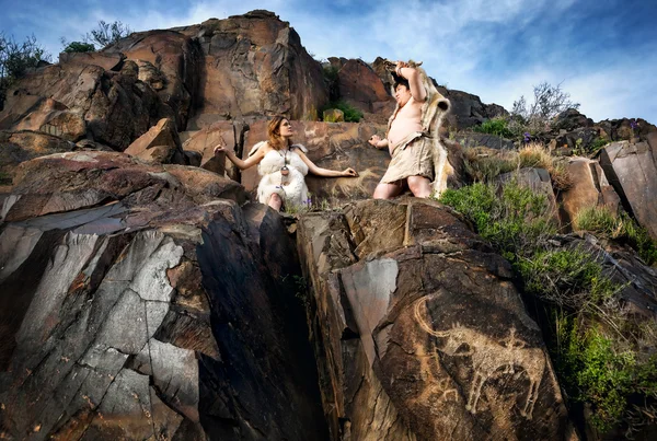 Cave people near drawing rock — Stock Photo, Image