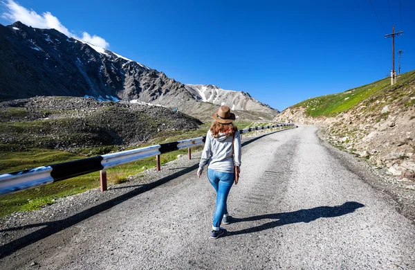 Mulher turística andando na estrada das montanhas — Fotografia de Stock