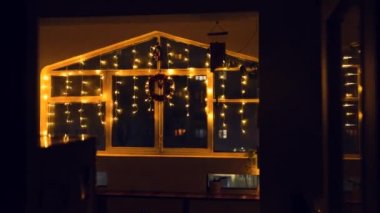 Atmosferik Noel penceresi sarı parlak ışıklarla dekore edilmiş.