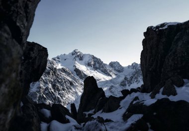 Kazakistan 'da kış vakti, yüksek dağlarda kar ve siyah kayalarla mavi gökyüzüne bakan güzel bir manzara. 