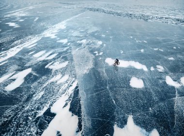 Buz desenli donmuş gölde bisiklet süren bir adamın en iyi görüntüsü..