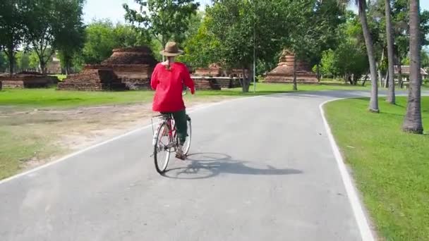 Vrouw fietsen in de buurt van tempel in Thailand — Stockvideo