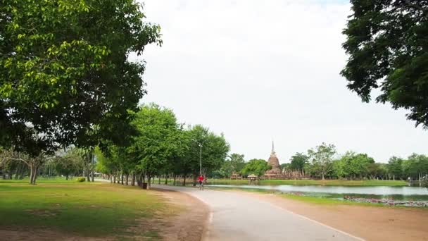 Vrouw fietsen in de buurt van tempel in Thailand — Stockvideo