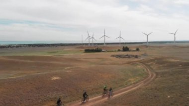 İnsanlar rüzgar türbini çiftliğine bisikletle gidiyor.