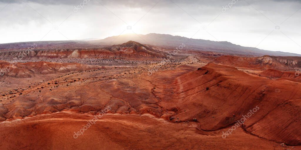 Aerial panorama of Red mountains Boguty in the desert canyon against sunset sky in Kazakhstan