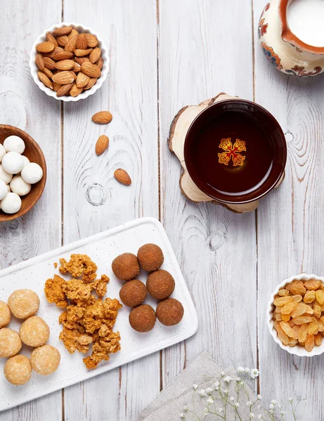 Kazakh national food like zhent, kurt, milk, sweet balls from cottage cheese, nuts and raisins during Nauryz festival on white wooden background.