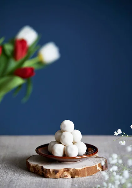 Kazakh and Kyrgyz national food kurt or kurut white salty balls from dry cheese near flowers during Nauryz festival at dark blue background. Free space for your text