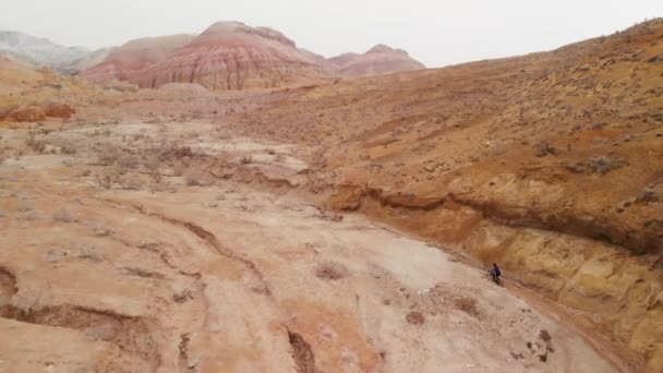 Drone tiro de passeio de bicicleta nas montanhas do deserto de cânion no Cazaquistão — Vídeo de Stock