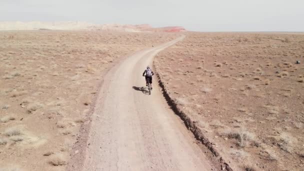 Drónfelvétel biciklis lovaglás a kanyon sivatagi hegyekben Kazahsztánban — Stock videók