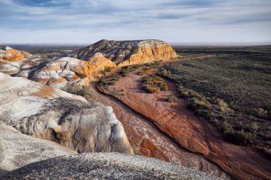 Kazakistan 'daki güzel milli parktaki kanyonlu tuhaf katmanlı kızıl çöl dağlarının hava aracı manzarası.