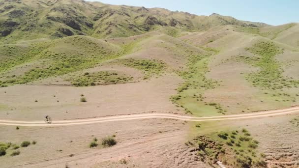 Strzał drona rowerzysty jazdy w górach Kazachstanu — Wideo stockowe