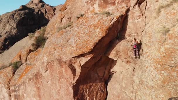 Fiatal nő mászik a magas sziklán — Stock videók