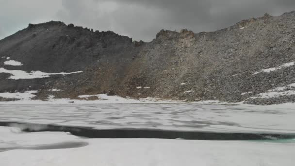 Вид с воздуха на горное озеро со льдом и снегом — стоковое видео