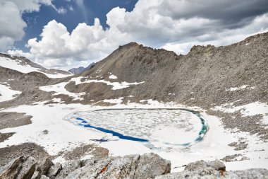 Kazakistan 'ın içinde buz parçaları olan mavi buzullu dağ gölünün güzel manzarası. İnsansız hava aracı ile hava görüntüsü