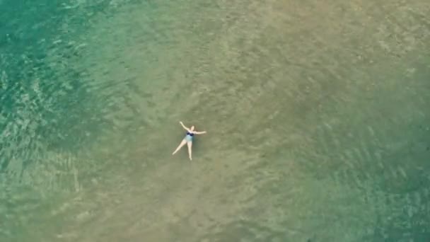 Vista aérea da jovem nadando na água do mar azul-turquesa transparente — Vídeo de Stock