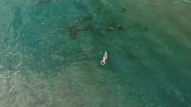 Vista aérea da jovem nadando na água do mar azul-turquesa transparente — Vídeo de Stock