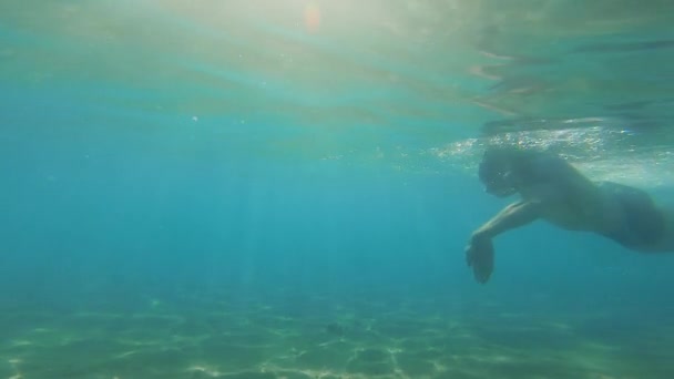 Podvodní pohled na člověka plavajícího v čisté vodě oceánu, zpomalený pohyb — Stock video