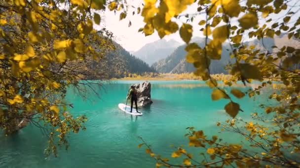 男オンスタンドアップパドルボードで山の湖 — ストック動画