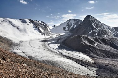 Tien Shan, Kazakistan 'da büyük buzulların ve kar dağlarının bulutlu mavi manzarası.. 