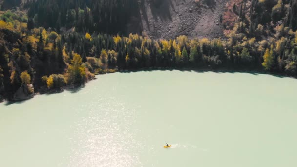 男は山の湖でいかだに乗って漕いでいる — ストック動画