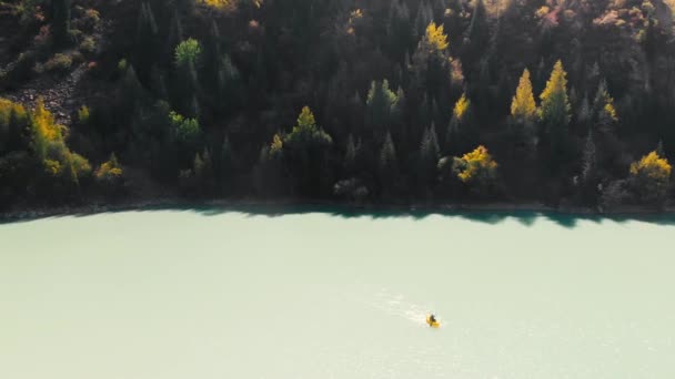 男は山の湖でいかだに乗って漕いでいる — ストック動画