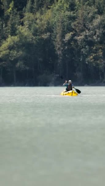 Människan paddlar på flotte båt i fjällsjön — Stockvideo