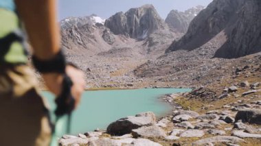 Sırt çantalı bir turist dağ gölü kenarında yürüyor.