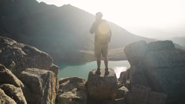 Hiker tourist with backpack taking photograph at smartphone at mountain lake — Stock Video