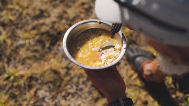 Чоловік їсть суп з локшиною в літньому таборі — стокове відео