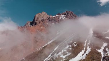 Dağ sırtı manzarasının havadan drone görüntüsü bulutlarda uçuşan bakir beyaz karla kaplı. Kazakistan 'ın Almaty şehrindeki Tien Shan Dağı
