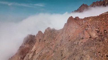 Dağ sırtı manzarasının havadan drone görüntüsü bulutlarda uçuşan bakir beyaz karla kaplı. Kazakistan 'ın Almaty şehrindeki Tien Shan Dağı