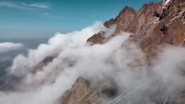 Dağ sırtı manzarasının havadan drone görüntüsü bulutlarda uçuşan bakir beyaz karla kaplı. Kazakistan 'ın Almaty şehrindeki Tien Shan Dağı