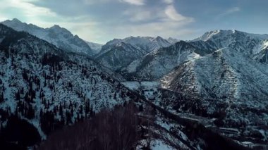 Dağ sırtı manzarasının havadan drone görüntüsü tepeler arasında saf beyaz karla kaplı. Kazakistan 'ın Almaty şehrindeki Tien Shan Dağı