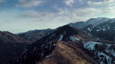 Dağ sırtı manzarasının havadan drone görüntüsü tepeler arasında saf beyaz karla kaplı. Kazakistan 'ın Almaty şehrindeki Tien Shan Dağı