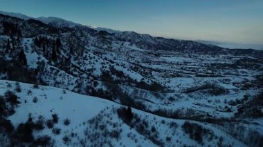 Oi Qaragai kayak merkezi Kazakistan 'daki bakir beyaz kar ve çam ağacı ormanlarıyla kaplı dağ vadisi manzarasının insansız hava aracı görüntüsü.