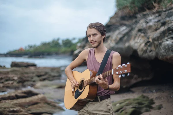 Romantische jongeman met een gitaar op het strand — Stockfoto