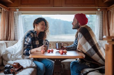 Karavanda bir masada oturan ve çay içen çift..