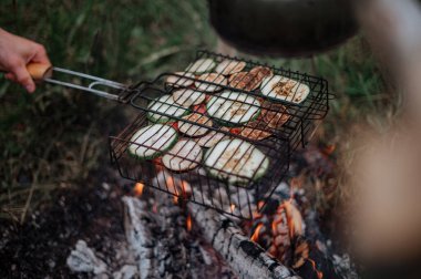 Kareli ekoseli bir çift, karavanın yanında lokum pişiriyor..
