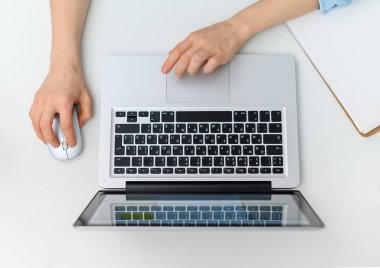 Dizüstü bilgisayarda yazı yazan ellerle çalışma alanı. Düz yatış, üst görünüm