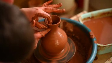 Potter atölyede çember tekerleği üzerinde çalışıyor.