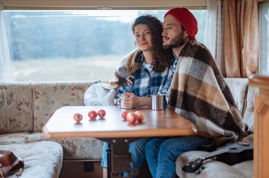 Karavanda bir masada oturan ve çay içen çift..