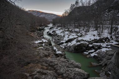 Gün batımında karlı dağ nehri. Yeşil renkli su