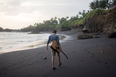 Sahilde gitar çalan romantik bir genç adam.