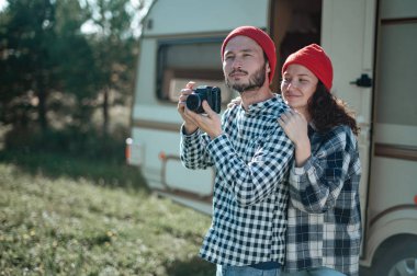 Kareli ekoseli bir çift, karavanın yanında lokum pişiriyor..