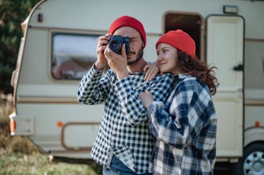 Kareli ekoseli bir çift, karavanın yanında lokum pişiriyor..