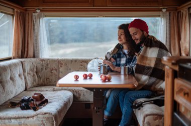 Kareli ekoseli bir çift, karavanın yanında lokum pişiriyor..