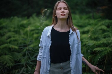 Meditasyon ve doğayla etkileşim pratiği. Yeşil ormandaki kız