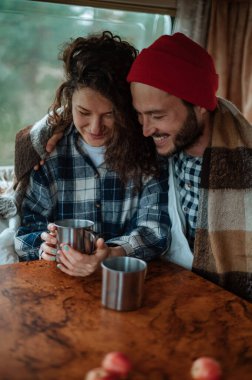 Karavanda bir masada oturan ve çay içen çift..