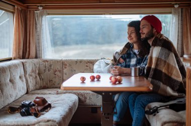 Karavanda bir masada oturan ve çay içen çift..