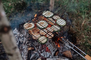 Kareli ekoseli bir çift, karavanın yanında lokum pişiriyor..